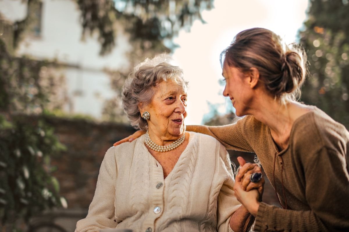 Adult daughter caring for her aging mother outdoors, supporting a parent without burning out