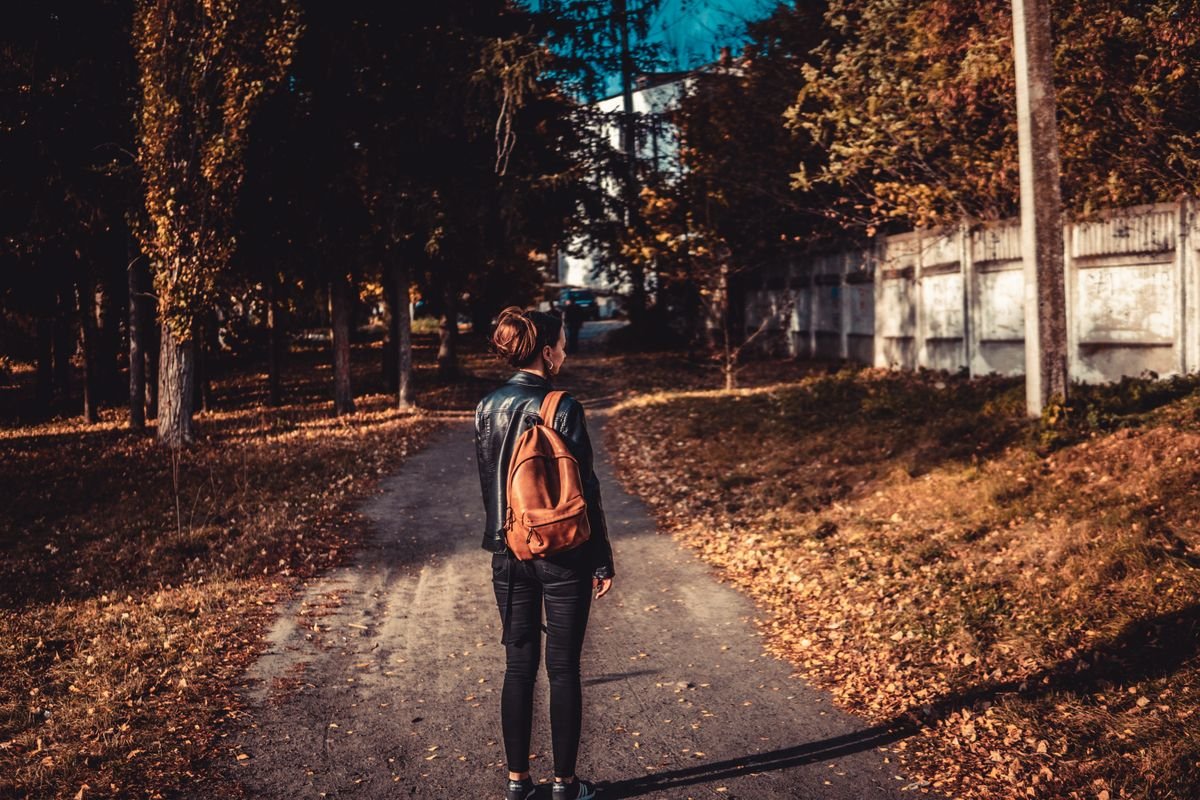 Woman walking alone on an autumn path, reflecting on life after divorce
