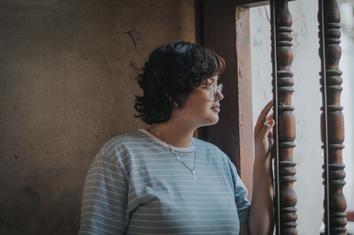 Woman looking out a window, taking time to rest after an immigration psychological evaluation
