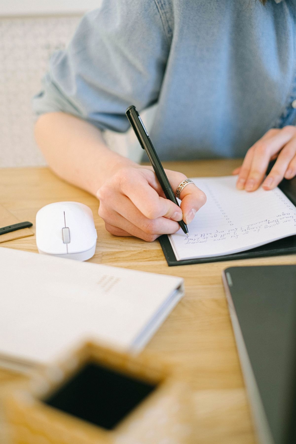 Person writing notes in a notebook before reaching out to a therapist